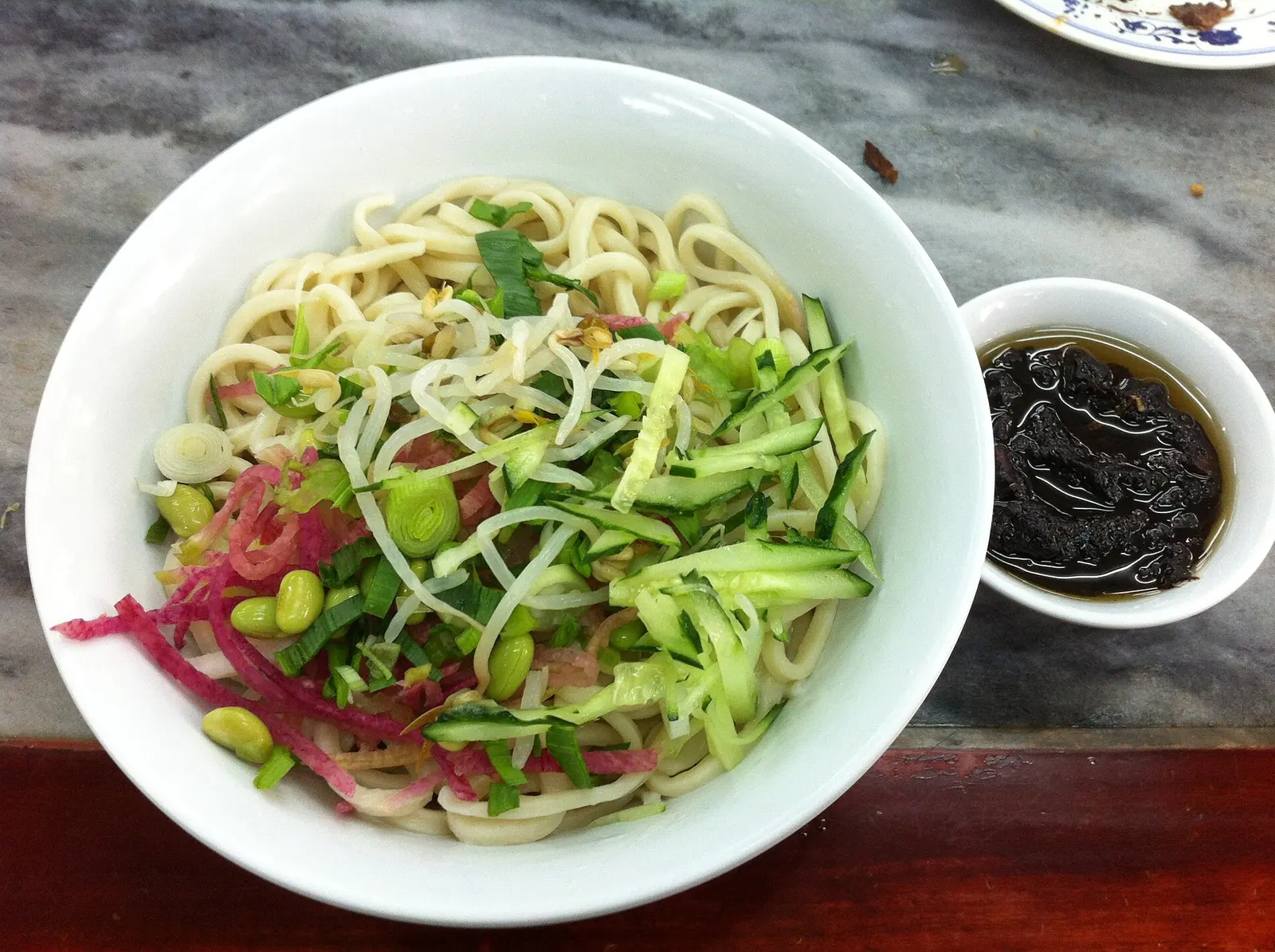 Zhajiangmian en un local de fideos de Ganjiakou, Pekín, con ocho acompañamientos de verduras antes de mezclar la salsa