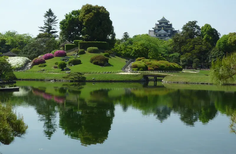 Paisaje junto al estanque del jardín Korakuen, con la negra torre del castillo de Okayama a lo lejos